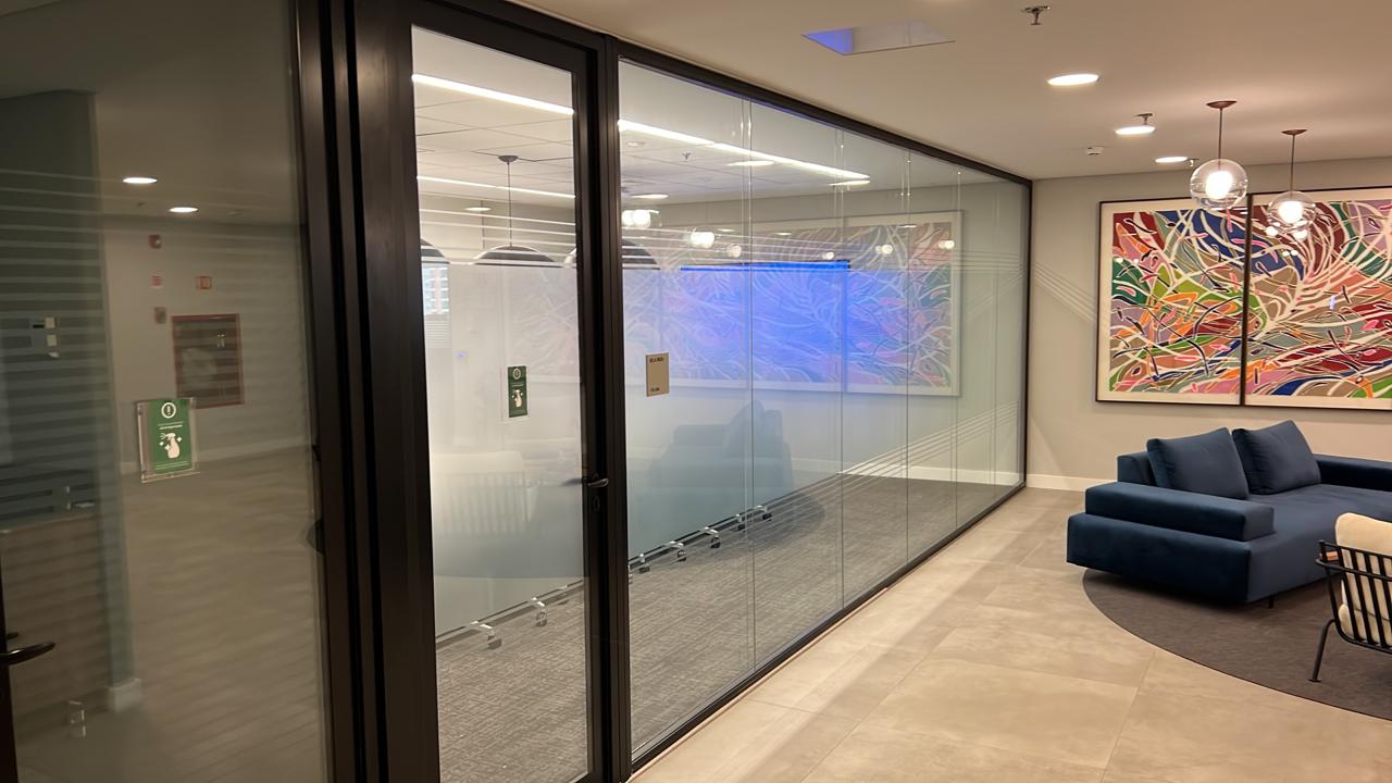 Corredor corporativo com divisórias de vidro jateadas